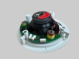 A ceiling fan motor assembly with a black speaker cone, green circuit board, and white mounting bracket, photographed on a light wood floor.