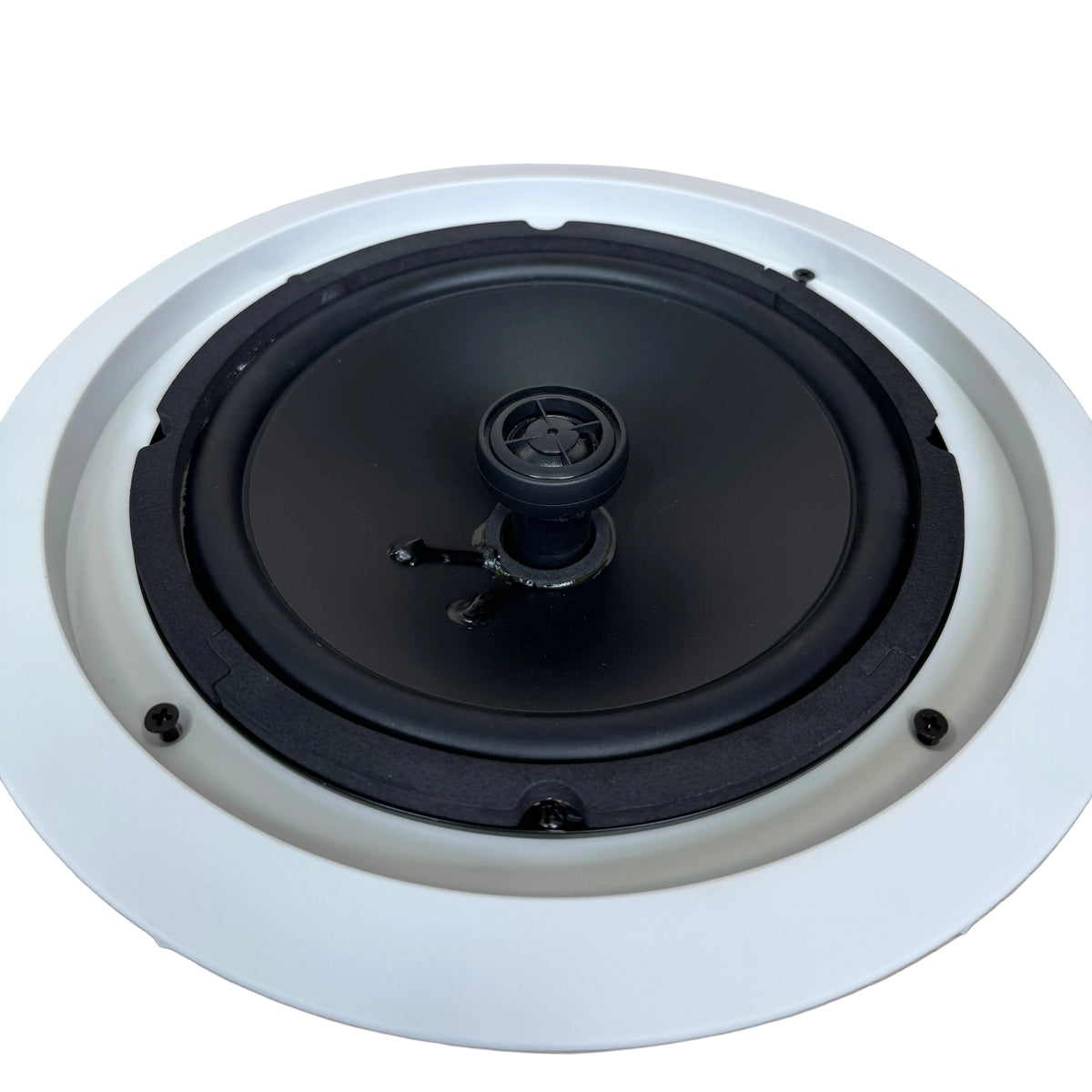 A ceiling-mounted recessed speaker with a black driver and a white circular frame, shown from a top-down perspective on a light wood floor.