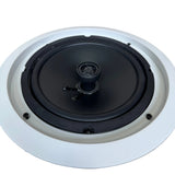 A ceiling-mounted recessed speaker with a black driver and a white circular frame, shown from a top-down perspective on a light wood floor.