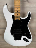 A white electric guitar with a black pickguard and maple neck, photographed from the side against a light wood plank background.