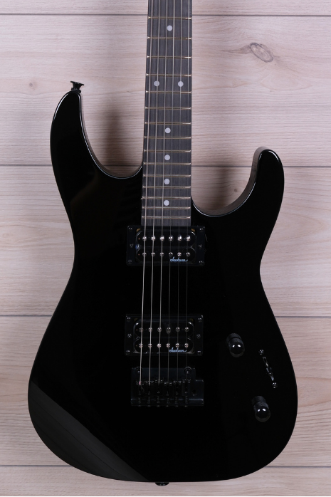 A black electric guitar with a glossy finish, resting vertically against a light wood plank wall. The headstock features the 'Aldam' brand logo in white script.