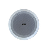 A round white ceiling speaker with a gray mesh grille, shown from a top-down view on a light wood plank floor.